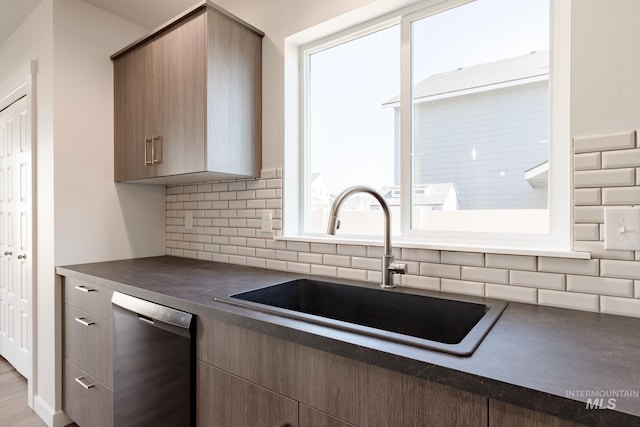 kitchen featuring dishwasher, backsplash, a healthy amount of sunlight, and sink