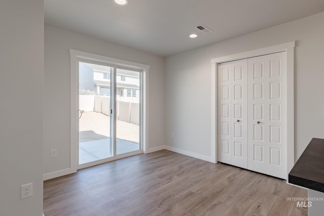 unfurnished bedroom featuring access to exterior, light wood-type flooring, and a closet