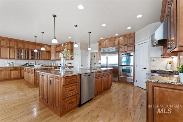 25374 W Deep Canyon Dr, Star, ID 83644 - kitchen with appliances with stainless steel finishes, an island with sink, a warming drawer, a sink, and brown cabinetry