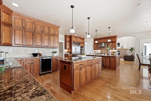25374 W Deep Canyon Dr, Star, ID 83644 - kitchen featuring appliances with stainless steel finishes, a kitchen island, arched walkways, brown cabinetry, and recessed lighting