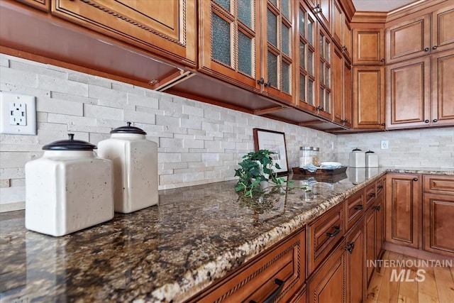 25374 W Deep Canyon Dr, Star, ID 83644 - kitchen featuring brown cabinetry, dark stone countertops, and glass insert cabinets