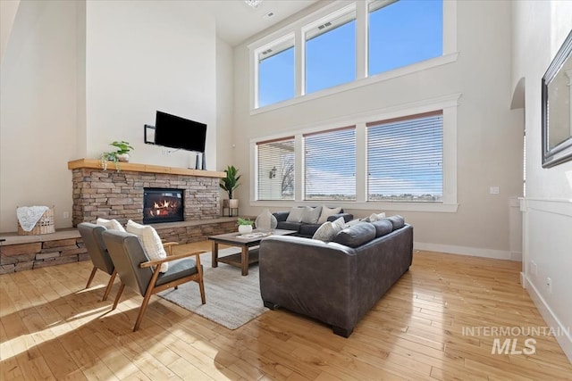 25374 W Deep Canyon Dr, Star, ID 83644 - living room featuring a high ceiling, light wood-type flooring, a stone fireplace, and baseboards