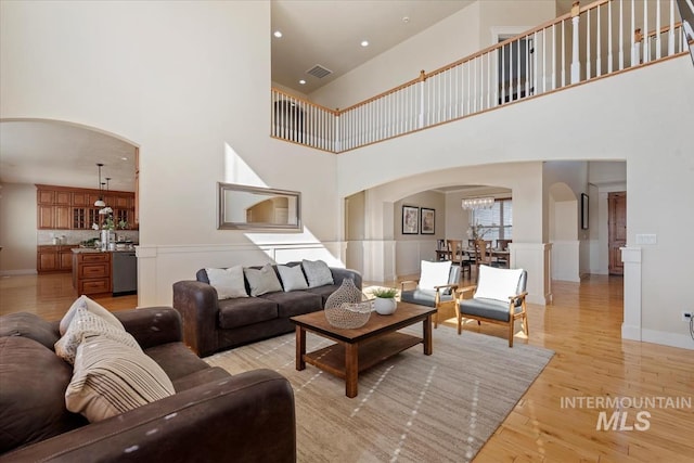 25374 W Deep Canyon Dr, Star, ID 83644 - living area with arched walkways, light wood-style floors, a towering ceiling, a wainscoted wall, and a chandelier