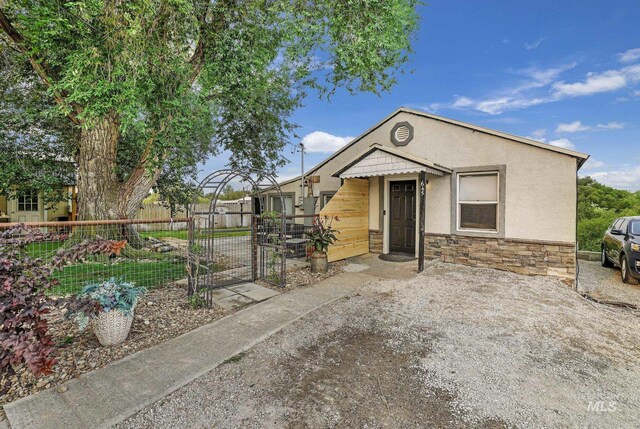 view of front of property with stone siding, fence, and stucco siding