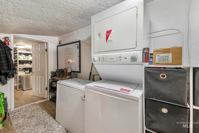 laundry room with stacked washing maching and dryer, hardwood / wood-style flooring, and a textured ceiling