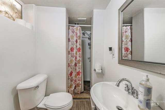 bathroom with walk in shower, toilet, hardwood / wood-style flooring, and sink