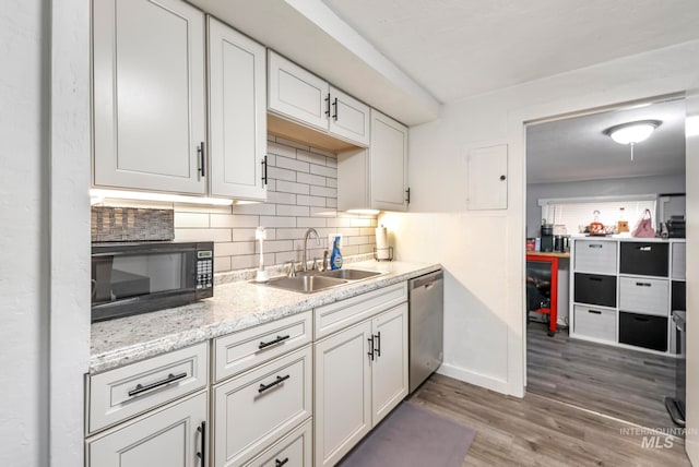 kitchen with hardwood / wood-style floors, backsplash, stainless steel dishwasher, sink, and white cabinetry