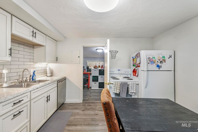 kitchen with white appliances, light hardwood / wood-style flooring, sink, decorative backsplash, and white cabinets