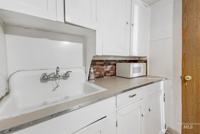 kitchen with decorative backsplash, white cabinetry, and sink