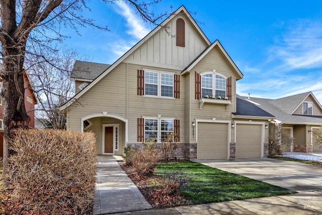 view of front of house with an attached garage, driveway, board and batten siding, and stone siding