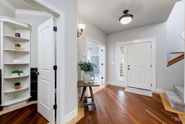 entryway featuring dark wood finished floors, baseboards, and stairs