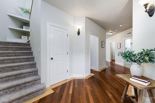 interior space featuring baseboards, a textured ceiling, visible vents, and wood finished floors