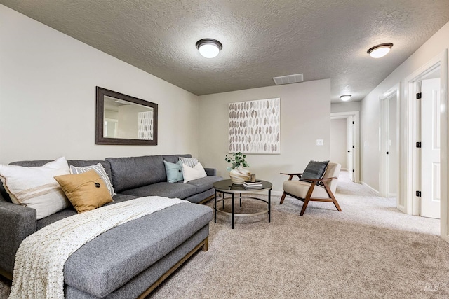 living room featuring light colored carpet, visible vents, a textured ceiling, and baseboards