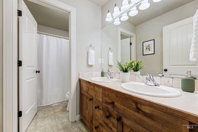 full bathroom featuring a sink, a textured ceiling, toilet, and double vanity