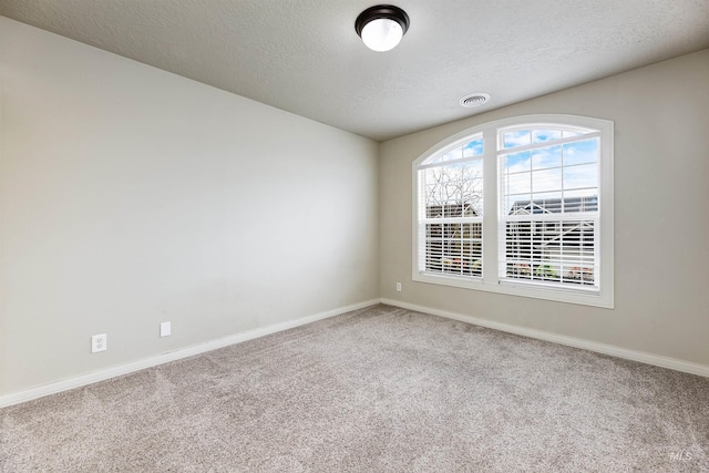 carpeted spare room featuring visible vents, a textured ceiling, and baseboards