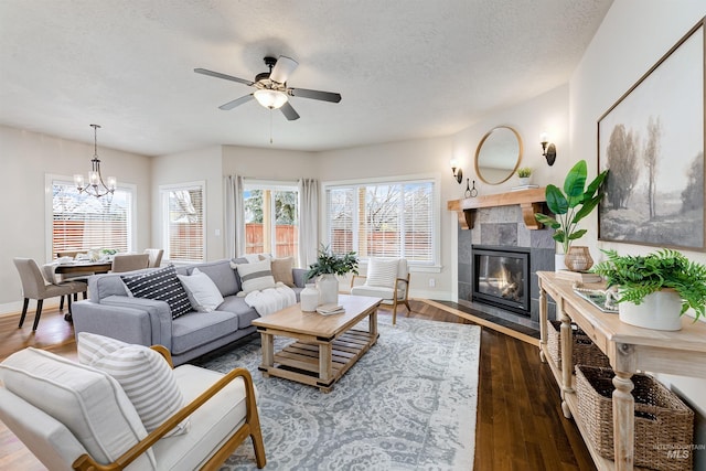 living room featuring a textured ceiling, dark wood-style flooring, a fireplace, and a wealth of natural light