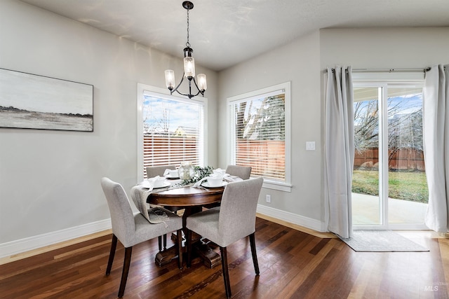 dining space featuring dark wood-type flooring, an inviting chandelier, and baseboards