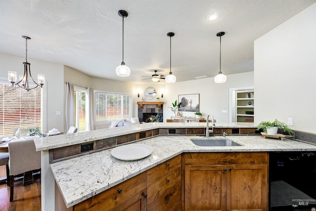 kitchen featuring open floor plan, dishwasher, a sink, and light stone countertops