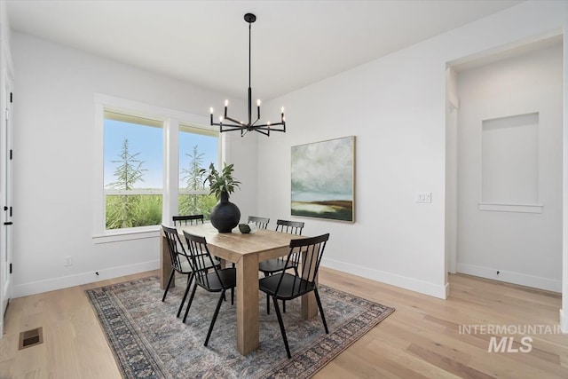 dining area with a notable chandelier, baseboards, visible vents, and light wood finished floors