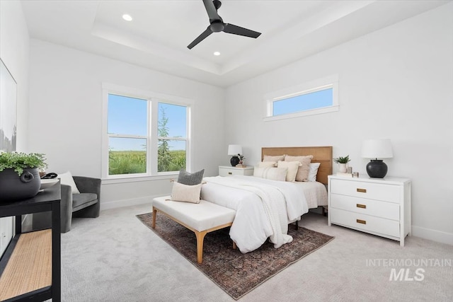 bedroom featuring a tray ceiling, baseboards, and light colored carpet