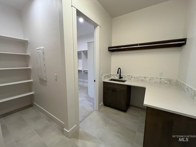 bar with light tile patterned flooring, baseboards, and a sink