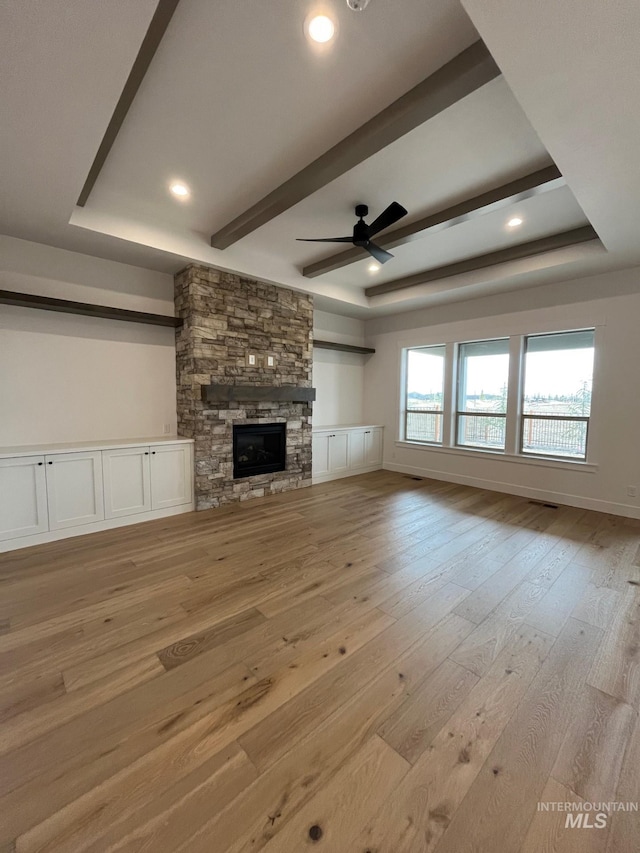 unfurnished living room featuring light wood finished floors and a tray ceiling