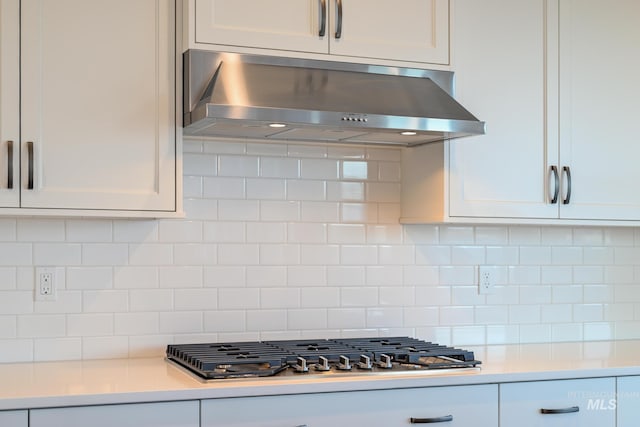 kitchen with white cabinetry, stainless steel gas stovetop, light countertops, decorative backsplash, and extractor fan