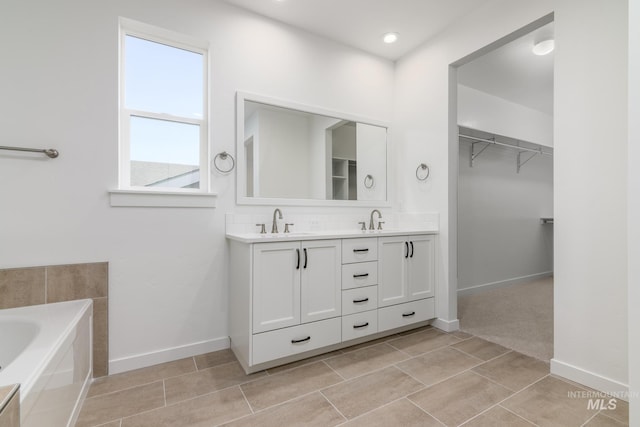 bathroom featuring decorative backsplash, double vanity, a spacious closet, and a sink