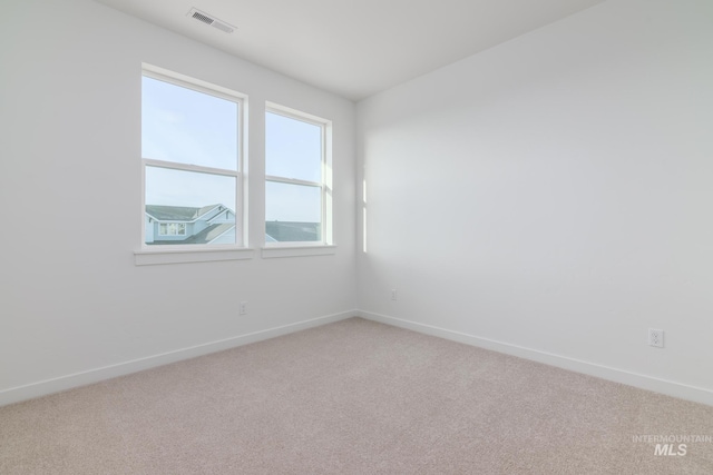 spare room with baseboards, visible vents, and light carpet