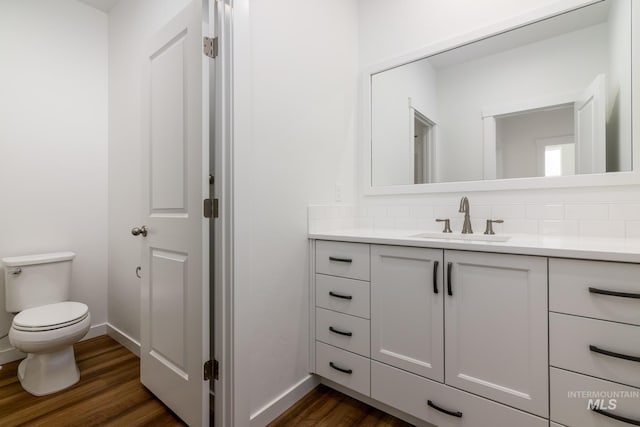 bathroom featuring backsplash, vanity, toilet, and wood finished floors