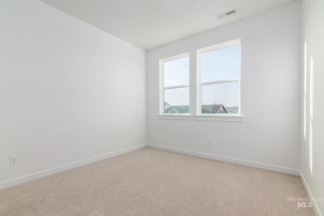 spare room with light carpet, visible vents, and baseboards