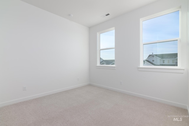 empty room featuring visible vents, light carpet, and baseboards