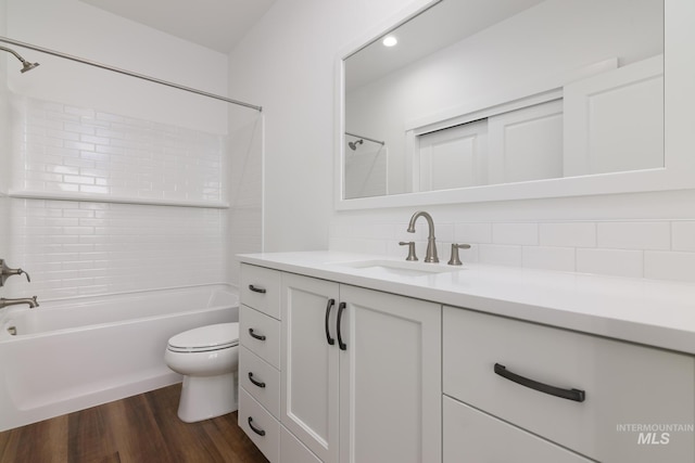 full bath featuring vanity, wood finished floors, bathtub / shower combination, toilet, and tasteful backsplash