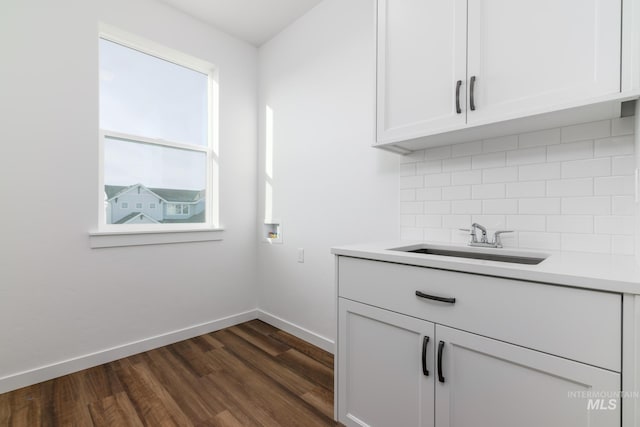 laundry area featuring baseboards, cabinet space, a sink, washer hookup, and dark wood-type flooring
