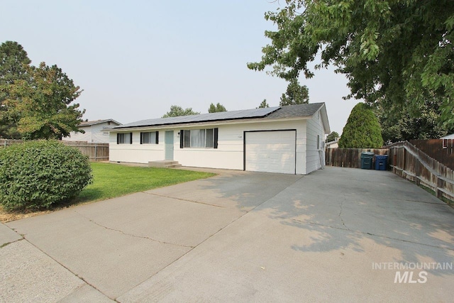 ranch-style house featuring a garage, a front lawn, and solar panels