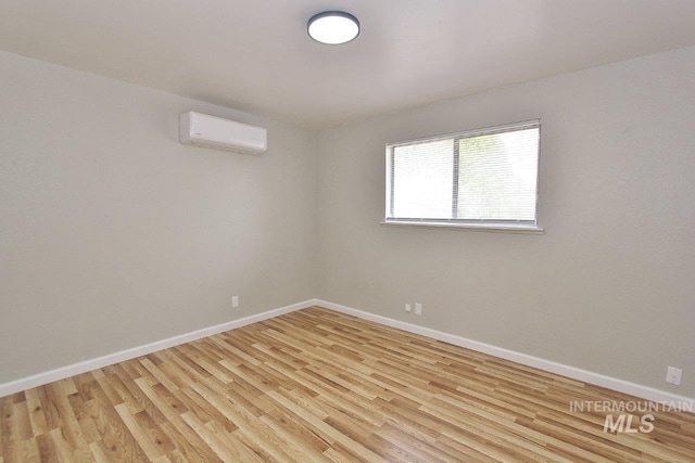 spare room with a wall mounted air conditioner and light wood-type flooring