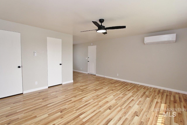 unfurnished room with ceiling fan, a wall mounted air conditioner, and light wood-type flooring