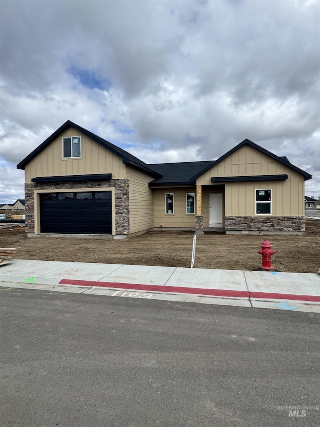 view of front of house with stone siding, board and batten siding, and an attached garage