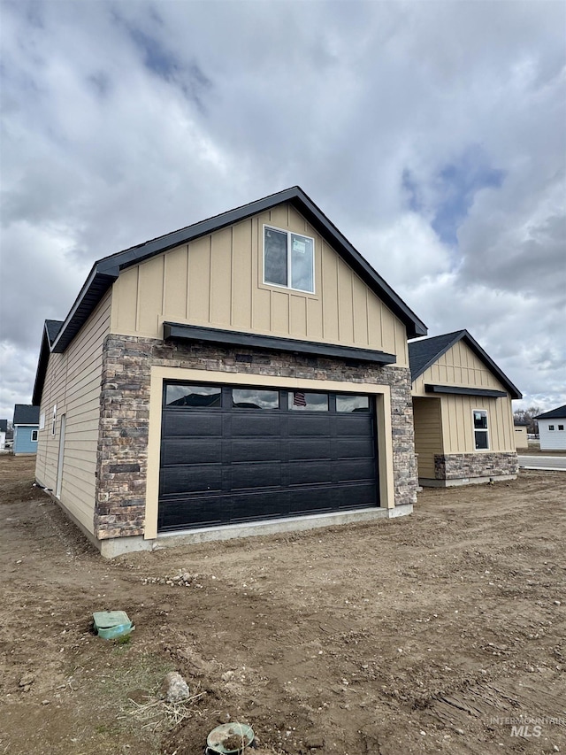 view of front facade with stone siding, board and batten siding, and a garage