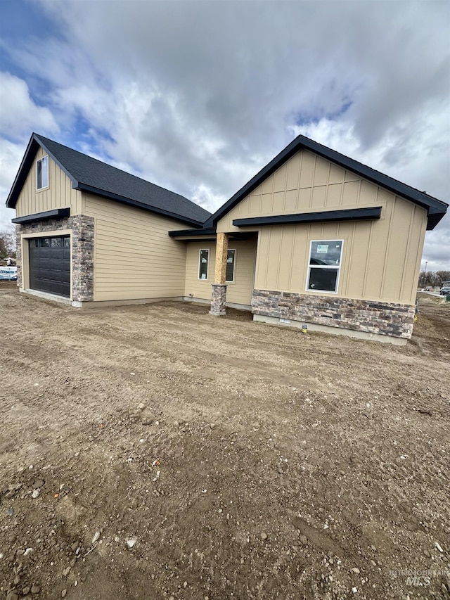 view of front facade with stone siding, a garage, and board and batten siding
