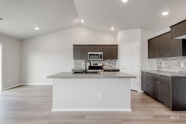 kitchen with dark brown cabinetry, sink, stainless steel appliances, and a center island with sink