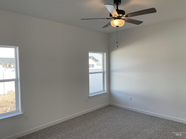 carpeted spare room with a ceiling fan and baseboards