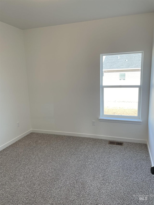 spare room featuring carpet floors, visible vents, and baseboards