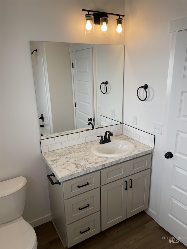 bathroom featuring wood finished floors, vanity, toilet, and baseboards