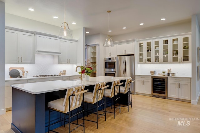 4014 W Farm View Dr, Boise, ID 83714 - kitchen featuring beverage cooler, stainless steel appliances, light countertops, a kitchen island with sink, and a sink