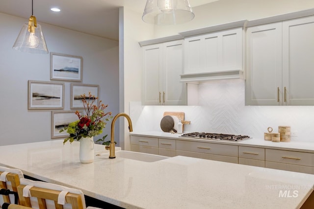 4014 W Farm View Dr, Boise, ID 83714 - kitchen featuring a sink, decorative backsplash, stainless steel gas cooktop, hanging light fixtures, and light stone counters