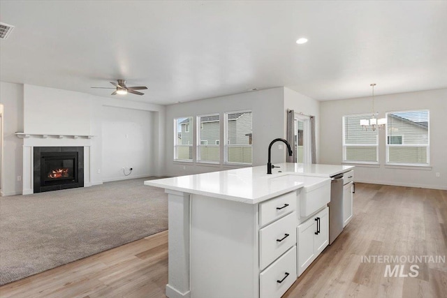 kitchen with light countertops, a sink, white cabinetry, dishwasher, and ceiling fan with notable chandelier