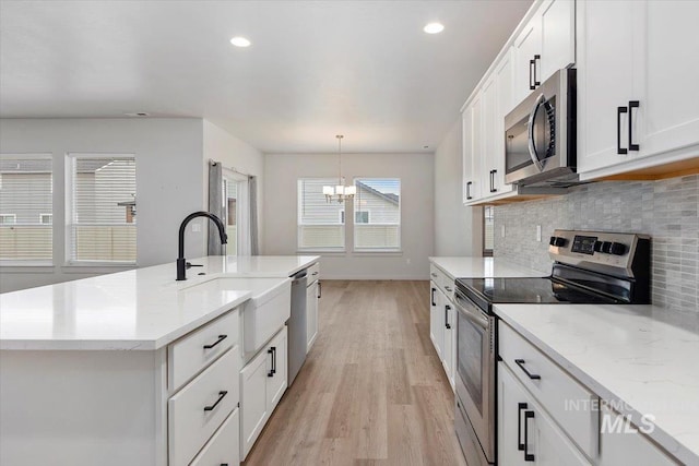 kitchen with white cabinets, light wood-style flooring, a chandelier, stainless steel appliances, and a sink