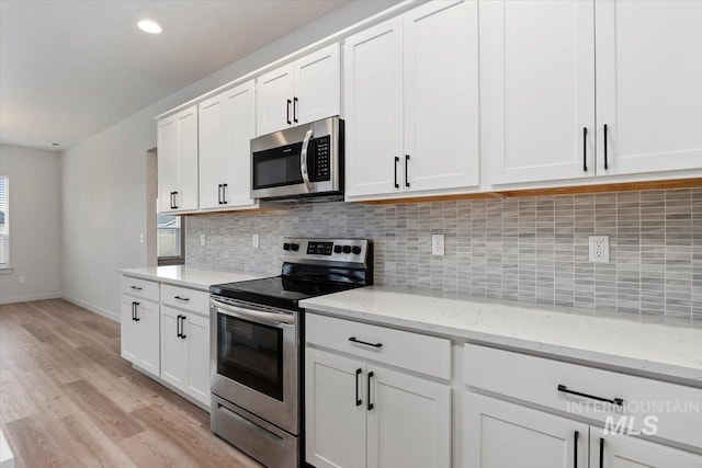 kitchen with white cabinetry, backsplash, light wood-type flooring, and appliances with stainless steel finishes