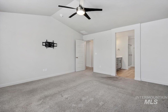 unfurnished bedroom with light colored carpet, vaulted ceiling, baseboards, ceiling fan, and ensuite bathroom